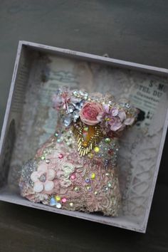 a small stuffed animal in a box with sequins and flowers