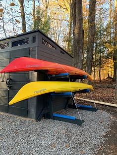 two canoes are sitting on the ground next to a storage shed in the woods