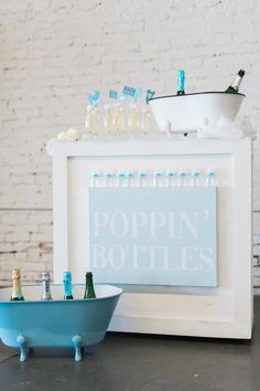 a blue bath tub sitting next to a white wall with bottles on it and a sign that says poppin'bottles