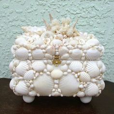 a white box with seashells on it sitting on a table next to a wall