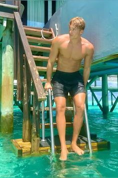 a man standing in the water next to a lifeguard tower with his leg up