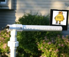 a sign that is on top of a white pole in front of a house and bushes