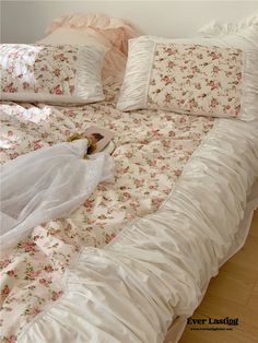 a white bed with pink flowers and ruffles on the comforter is shown