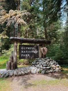 the olympic national park entrance sign is surrounded by rocks and pine trees in the background