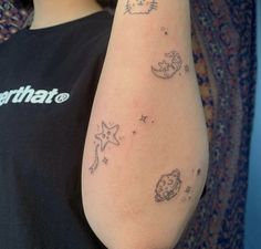 a woman's arm with tattoos on it that include cats and moon, stars