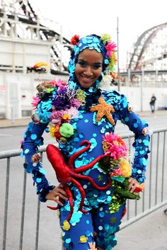 a woman dressed as a clown standing in front of a roller coaster