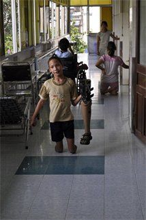 a young boy walking down a hallway next to a woman in a white shirt and black shorts