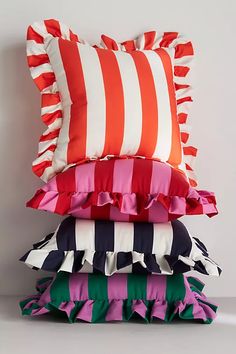 four pillows stacked on top of each other in different colors and patterns, one with ruffled edges