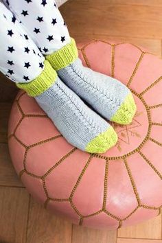 the legs of a person wearing socks and leggings sitting on a pink ottoman