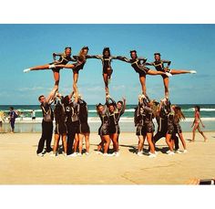 a group of people standing on top of each other in front of the ocean holding onto one another