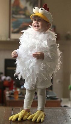 a little boy dressed as a chicken standing on top of a table