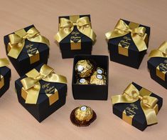 six black boxes with gold ribbons and chocolates