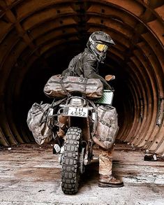 a man riding on the back of a motorcycle in front of a large metal pipe