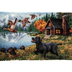 a black dog standing on top of a grass covered field next to a lake with ducks flying over it