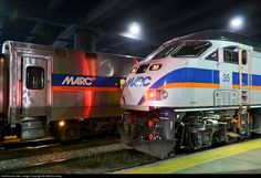 a silver and blue train is on the tracks at night time with its lights on