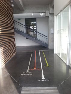 an empty parking garage with stairs leading up to the second floor and two sets of glass doors