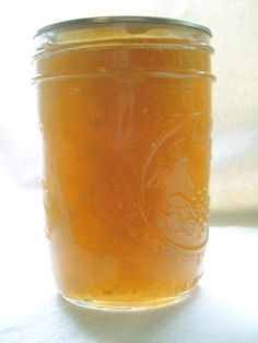 a glass jar filled with liquid sitting on top of a white tablecloth next to a window