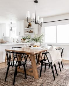 a dining room table with four chairs and a rug on the floor in front of it