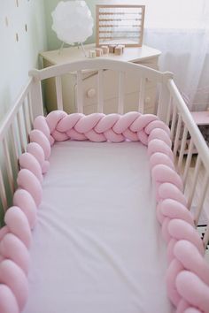 a baby crib with pink pillows on it