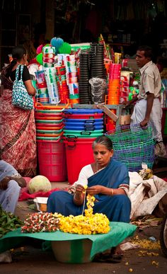 a woman sitting in front of a fruit stand