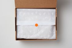 an open box with a white cloth and orange dot on the top, sitting on a table