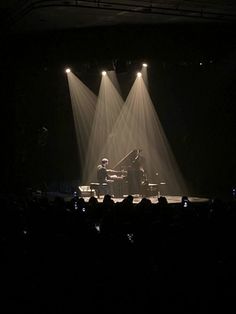 two people on stage playing piano in the dark