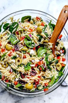 a bowl filled with pasta salad on top of a marble counter