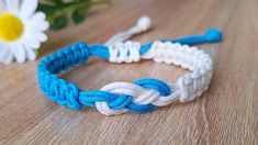 two blue and white bracelets sitting on top of a wooden table next to flowers