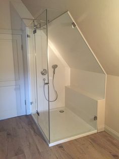 an empty bathroom with a glass shower and wooden floors in the corner of the room