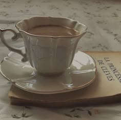 a cup of hot chocolate sitting on top of a saucer next to a book