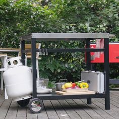 an outdoor kitchen cart on a deck with fruit and water in the backgroud