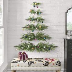 a white brick wall with a christmas tree hanging on it's side next to a bench