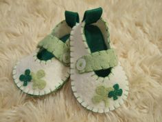 a pair of green and white baby shoes sitting on top of a fluffy carpet covered floor