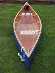 a blue and brown boat sitting on top of green grass next to a fenced in area