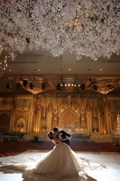 a bride and groom pose for a wedding photo in front of an elaborately decorated stage