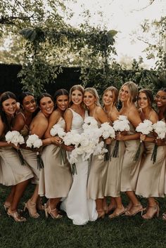 a group of women standing next to each other holding bouquets