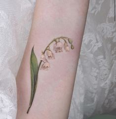 a small pink flower on the arm with green stems and leaves attached to it's side