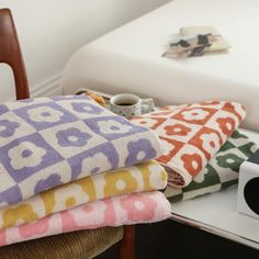 a stack of towels sitting on top of a wooden chair next to a white bed