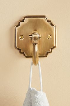 a white towel hanging from a hook on a wall with a gold plated handle