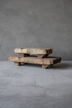 two wooden benches sitting on top of a cement floor in front of a gray wall