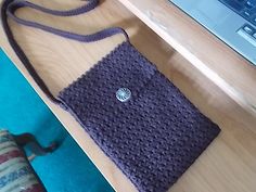 a purple bag sitting on top of a wooden table next to a laptop computer and mouse