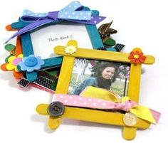 a small wooden frame with flowers on it and a photo hanging from the side, in front of a white background