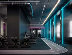 an empty gym with rows of treadmills and neon lights on the wall behind them