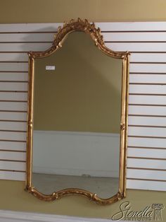 a gold framed mirror sitting on top of a mantle