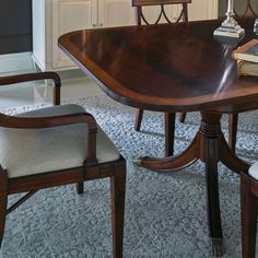 a dining room table with two chairs and a book on it's end shelf