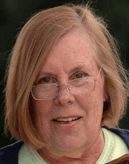 an older woman with glasses holding a wooden spoon