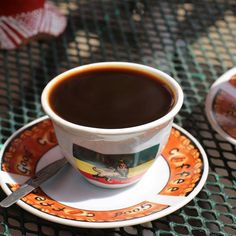 a cup of coffee sitting on top of a saucer next to a plate with a spoon