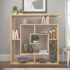 a shelf with books, vases and other items on it in a living room