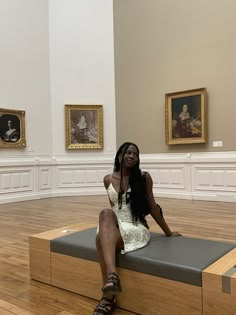 a woman sitting on top of a bench in a museum