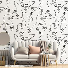 a living room with a couch, mirror and wallpaper that has faces drawn on it